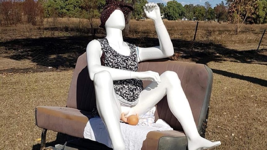 A mannequin positioned on a chair like it's giving birth to a doll on the side of the road