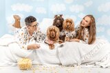 Lauren and Naomi in a stylised photoshoot in their PJs and on a bed with their three dogs