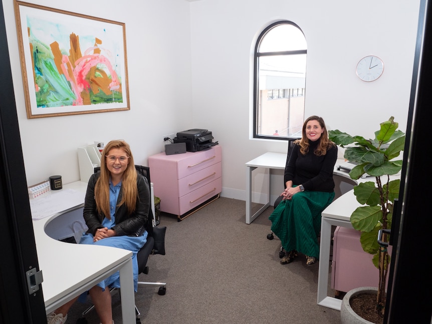 Two women sitting inside a shared co-working office.