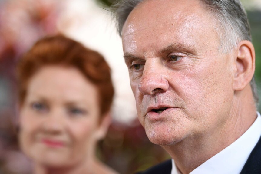 Mark Latham speaks with Pauline Hanson in the background.