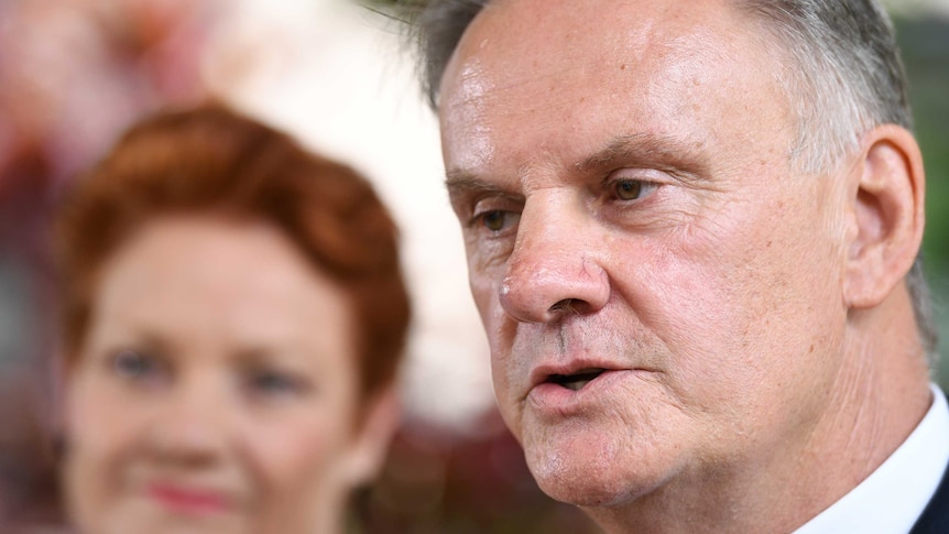 Mark Latham speaks with Pauline Hanson in the background.