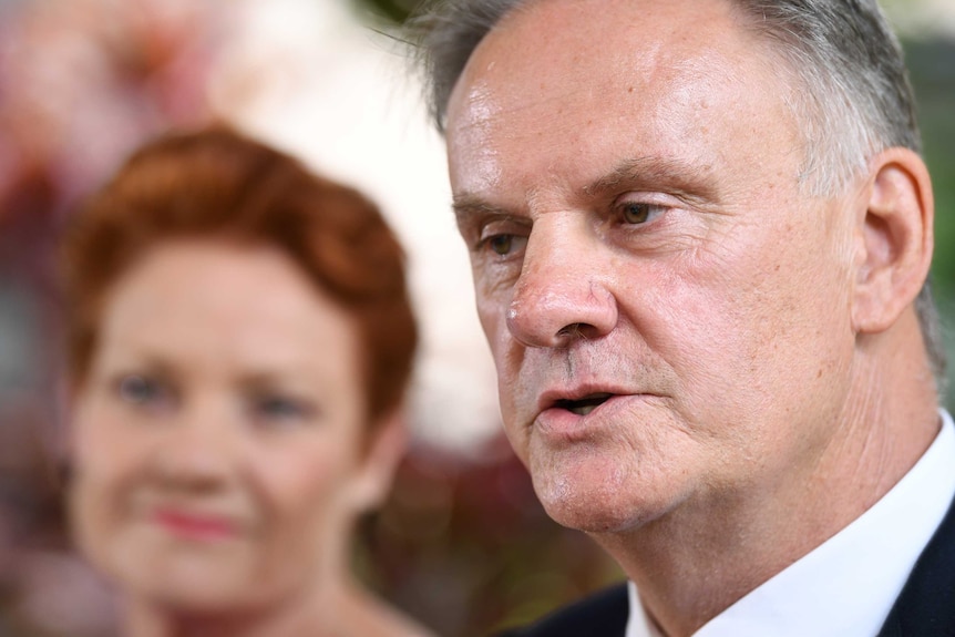 Mark Latham speaks with Pauline Hanson in the background.