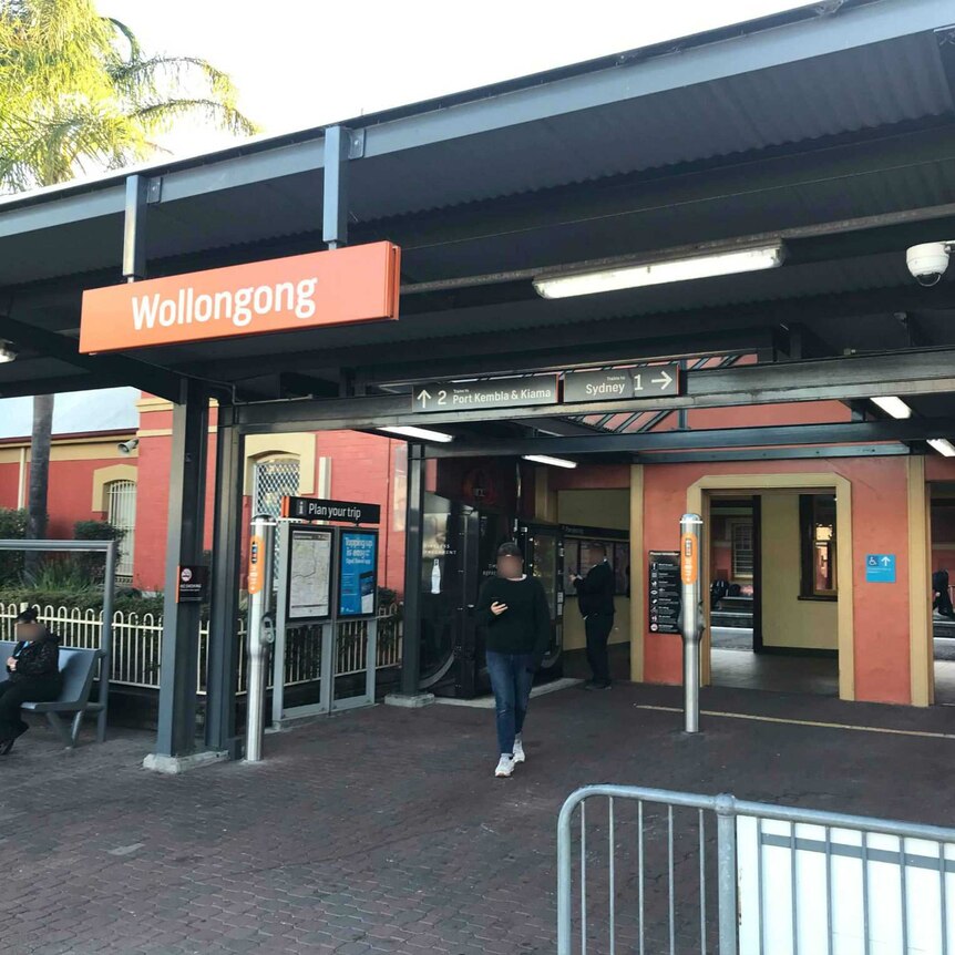 A railway station platform with a red sign saying Wollongong.