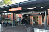 A railway station platform with a red sign saying Wollongong.