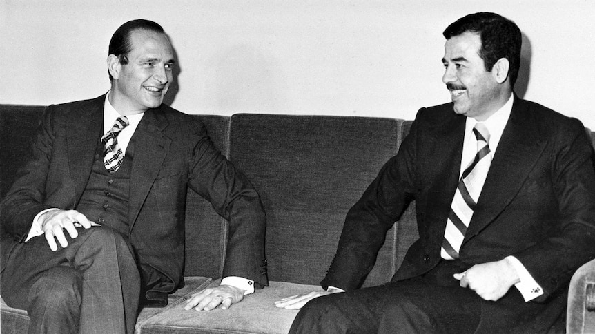 Jacques Chirac sits on a couch smiling with Saddam Hussein.