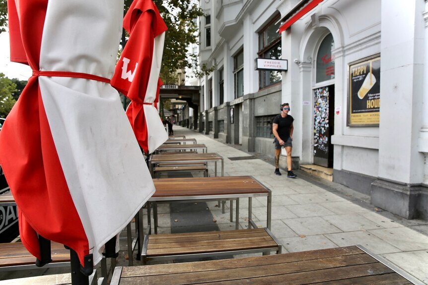 A red and white umbrella stands next to outdoor seating on the footpath outside Freddie Wimpole's.