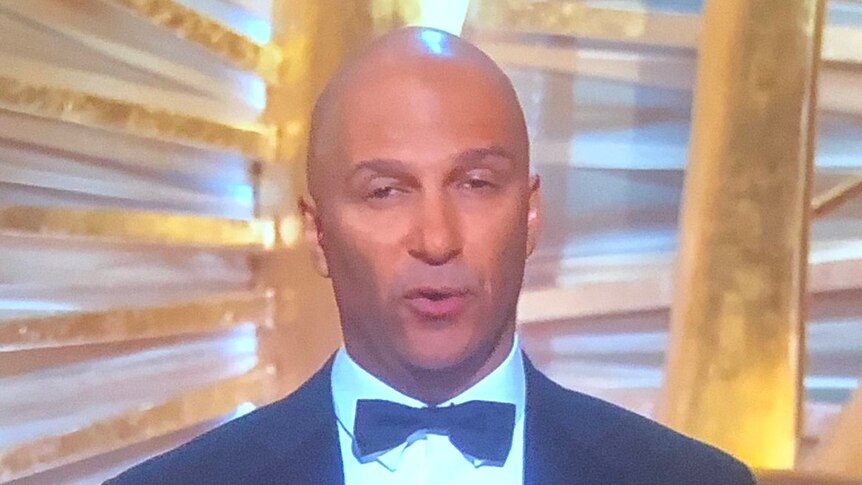 Tom Morello in a bow tie and suit on stage at the Oscars