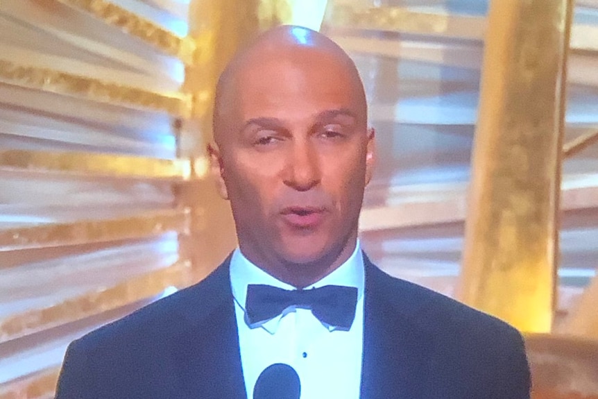 Tom Morello in a bow tie and suit on stage at the Oscars
