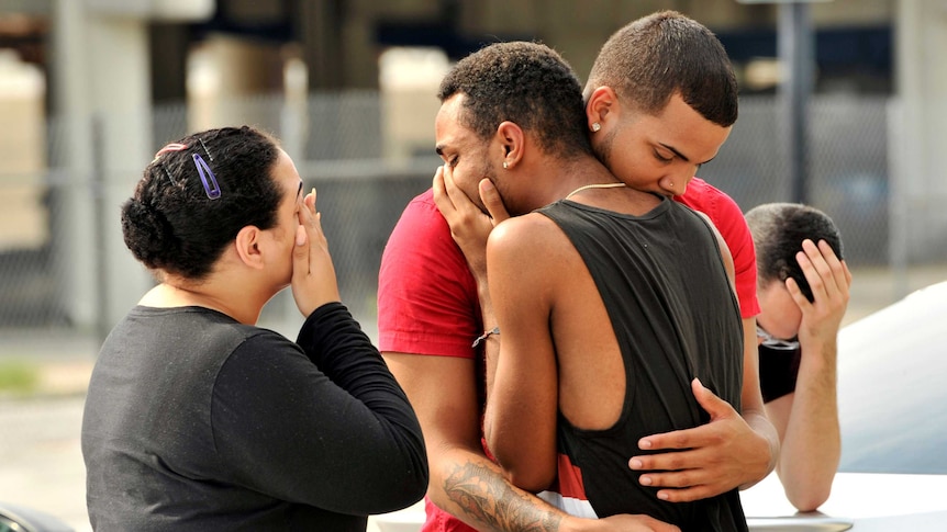 Friends and family members embrace outside the Orlando Police Headquarters