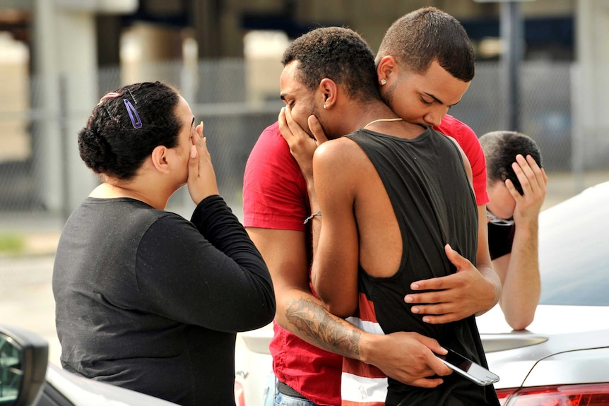 Friends and family members embrace outside the Orlando Police Headquarters