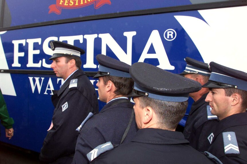 Policemen are on guard next to a Festina team bus before stage five of Tour de France, 1998.