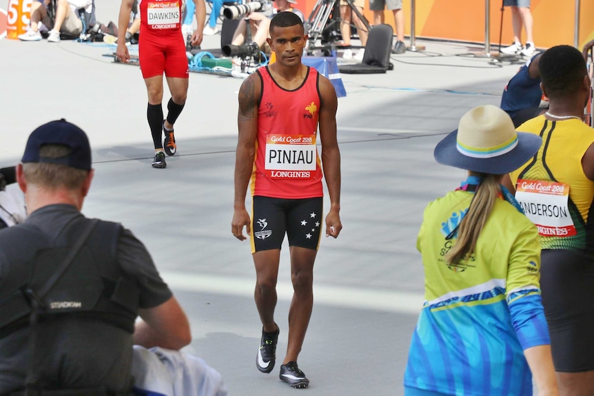 Cameras and officials surround Theo as he walks off the track.