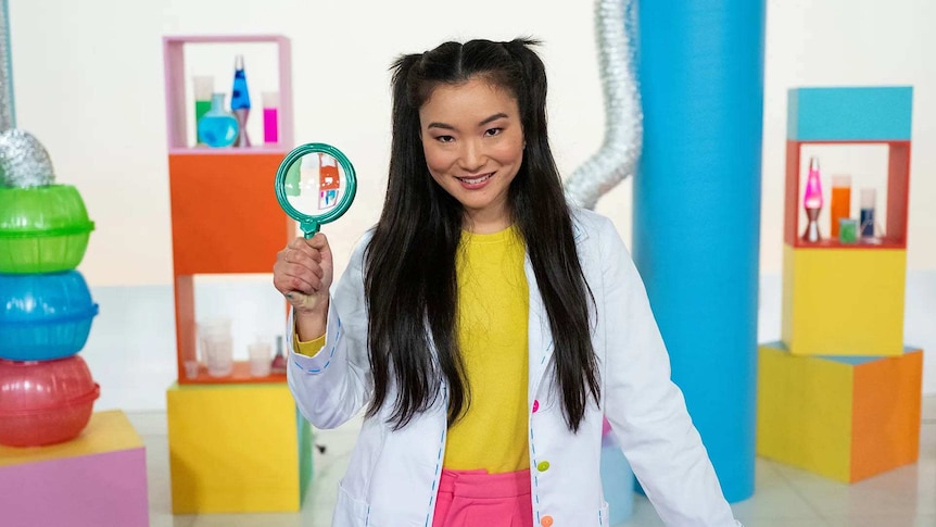 Michelle holding a magnifying glass on the set of Play School Science Time