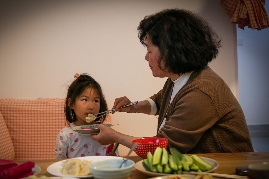 A woman feeds a dumpling to a child 
