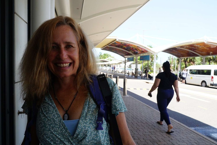 Rebecca Clare smiles at the camera in a green dress outside Darwin airport.