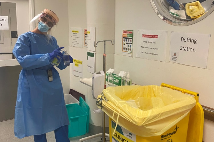 Emily Morris at work at the Royal Melbourne Hospital wearing full protective equipment and holding hand sanitiser