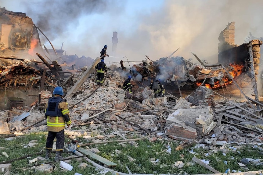 Emergency crew work on top of smouldering debris.