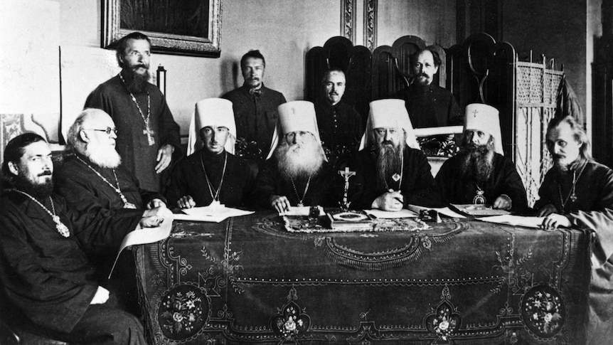 A group of Russian Orthodox men sit around an adorned table.