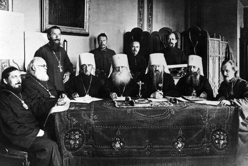 A group of Russian Orthodox men sit around an adorned table.