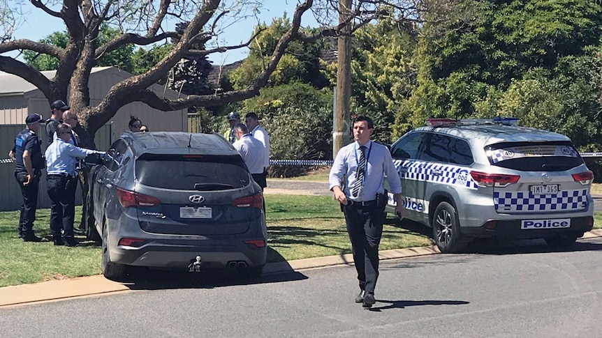 A crime scene at a house with cars parked outside.