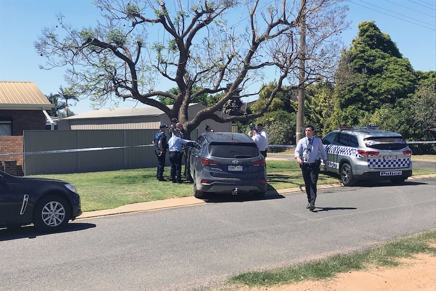 A crime scene at a house with cars parked outside.