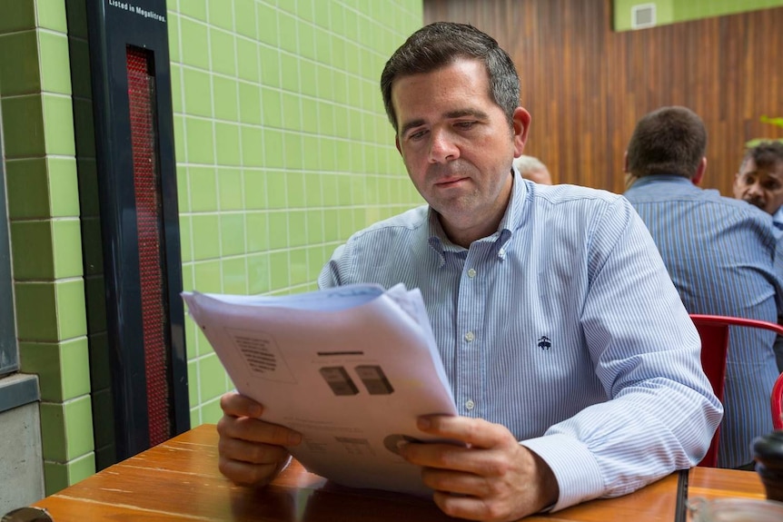 Economist Gene Tunny looks at documents at a cafe in South Brisbane