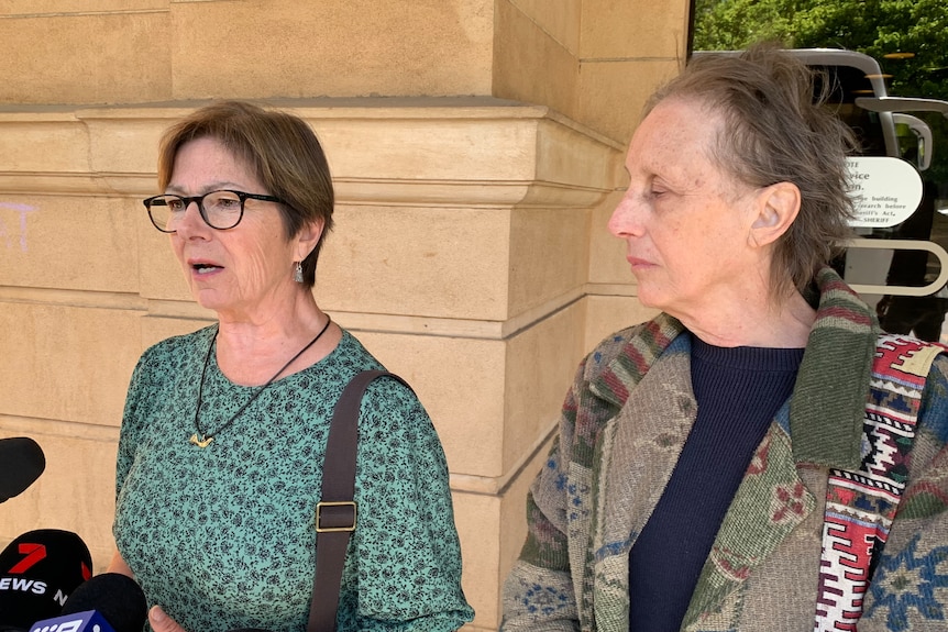 Two women speak to the media outside court.