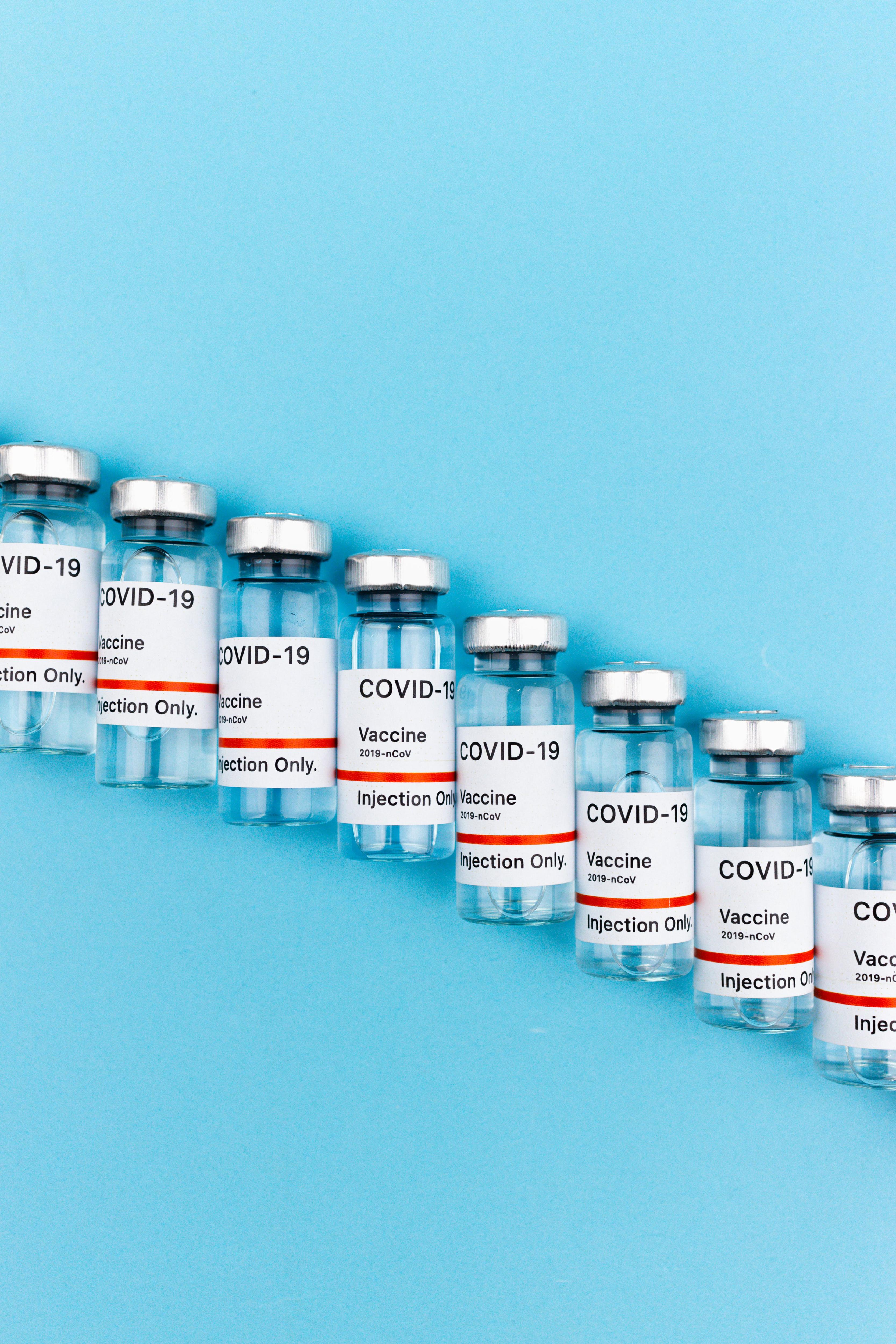 A generic stock photo of a row of COVID-19 vaccines against a blue background.