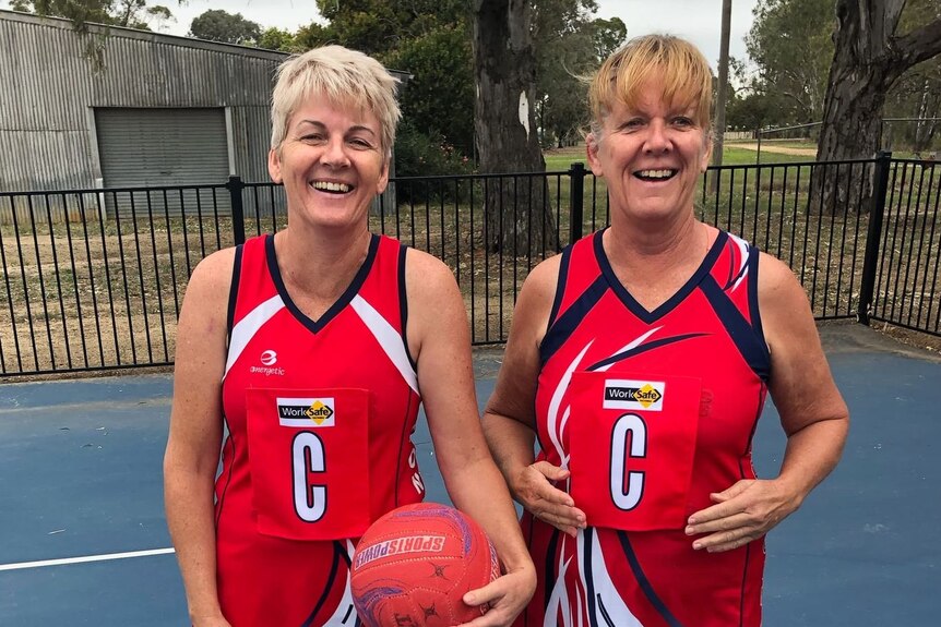 Wendy Sidebottom and a friend stand side by side on a netball court.