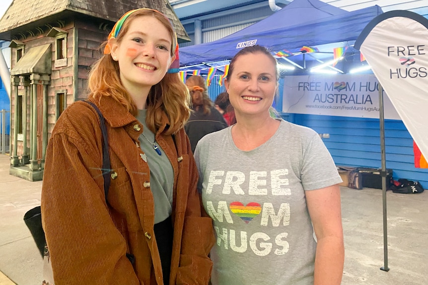Two women standing smiling with rainbow shirts or face paint