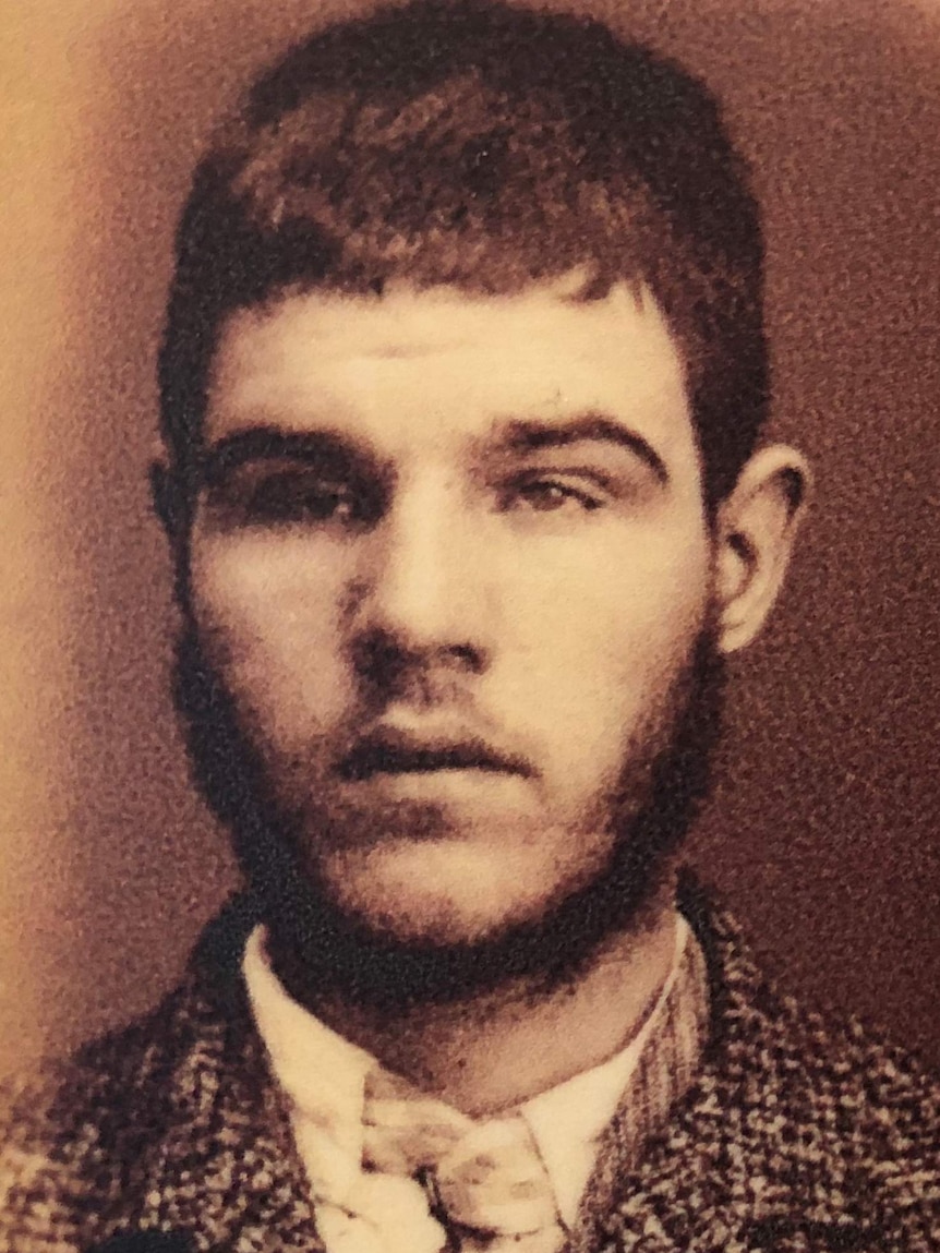 A black and white photo of a young man with closely cropped dark hair.