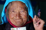 An Afghan resident holds her voter card after casting her ballot at a polling station in Bamiyan province on June 14, 2014.
