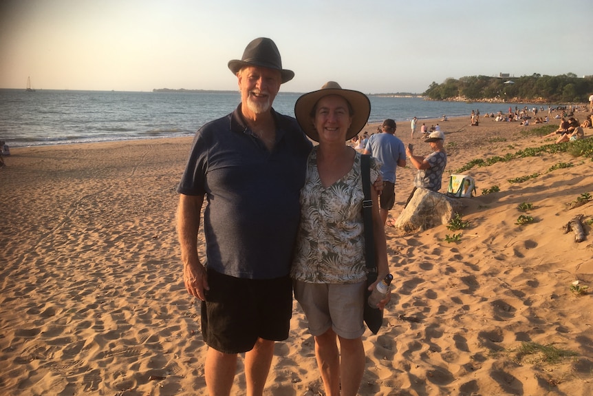 An older man and woman smiling on a beach.