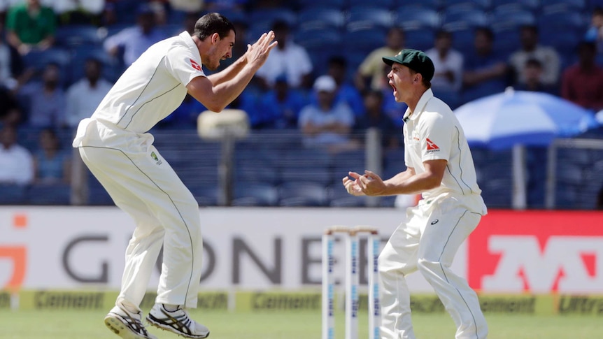 Mitchell Starc (L) and Steve O'Keefe celebrate the dismissal of India captain Virat Kohli in Pune.