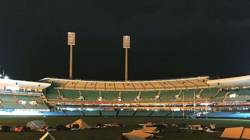 People sleep under cardboard boxes at the SCG at night