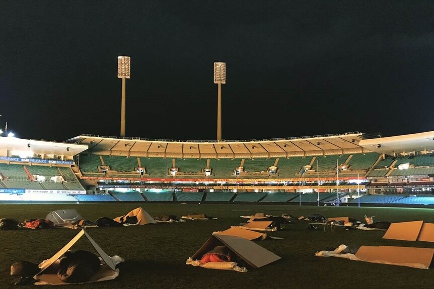 People sleep under cardboard boxes at the SCG at night