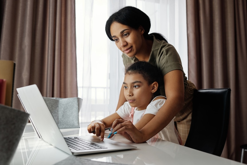 A woman and child look at a computer together for a story on early puberty in children. 