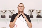 Fanning stands with surfboard and trophies
