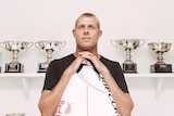 Fanning stands with surfboard and trophies