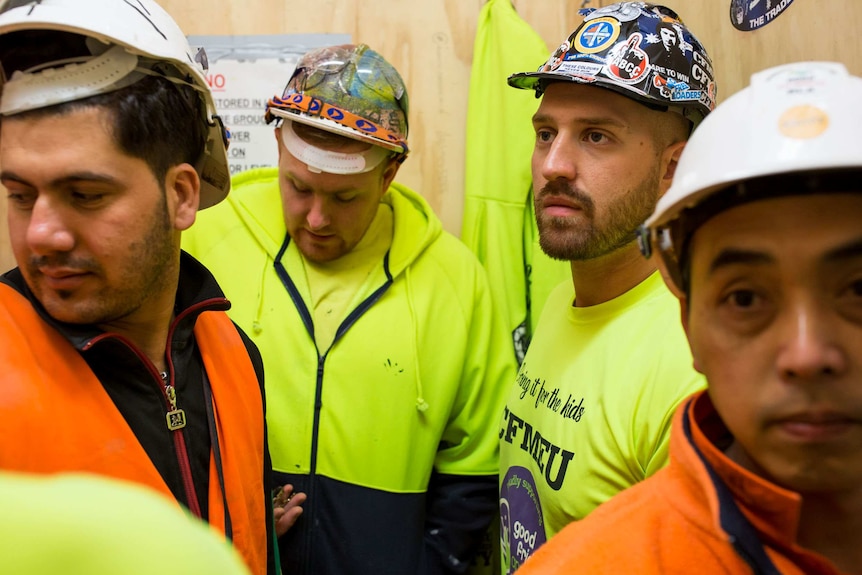 Paul Tzimas in a lift on a construction site with other workers.