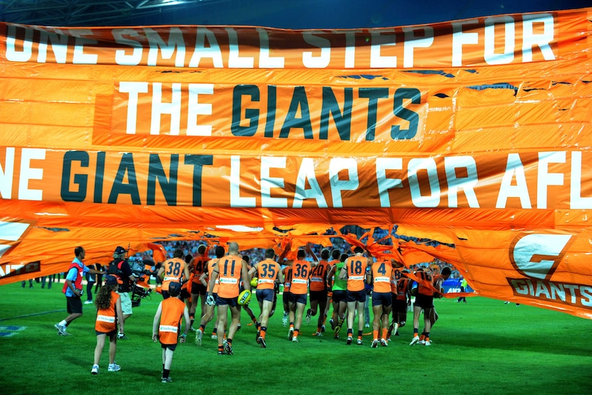 Football team runs through a banner.