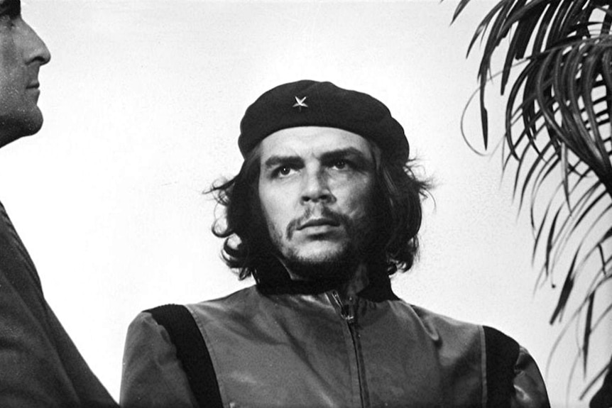 A black and white image of Che Guevara, with long hair and beret