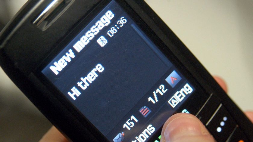 A hand holds a mobile phone as it writes a text message