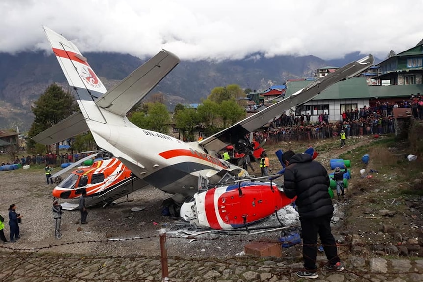 Crowds of people surround a crash between an aircraft and a helicopter in Nepal.