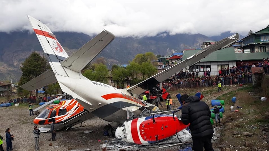 Crowds of people surround a crash between an aircraft and a helicopter in Nepal.