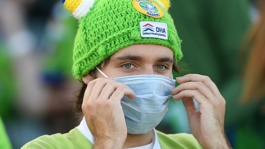 A Raiders fan wears a mask and a green, viking-themed bobble hat