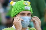 A Raiders fan wears a mask and a green, viking-themed bobble hat