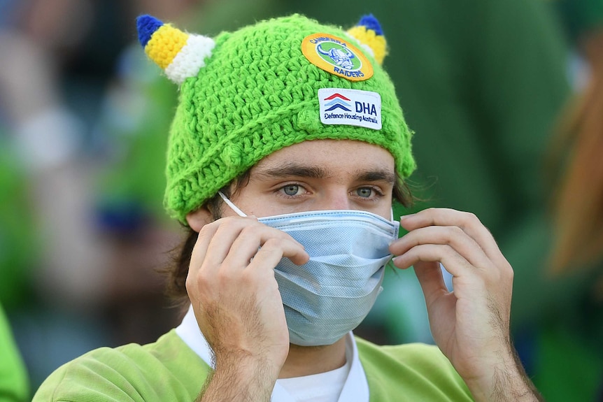 A Raiders fan wears a mask and a green, viking-themed bobble hat