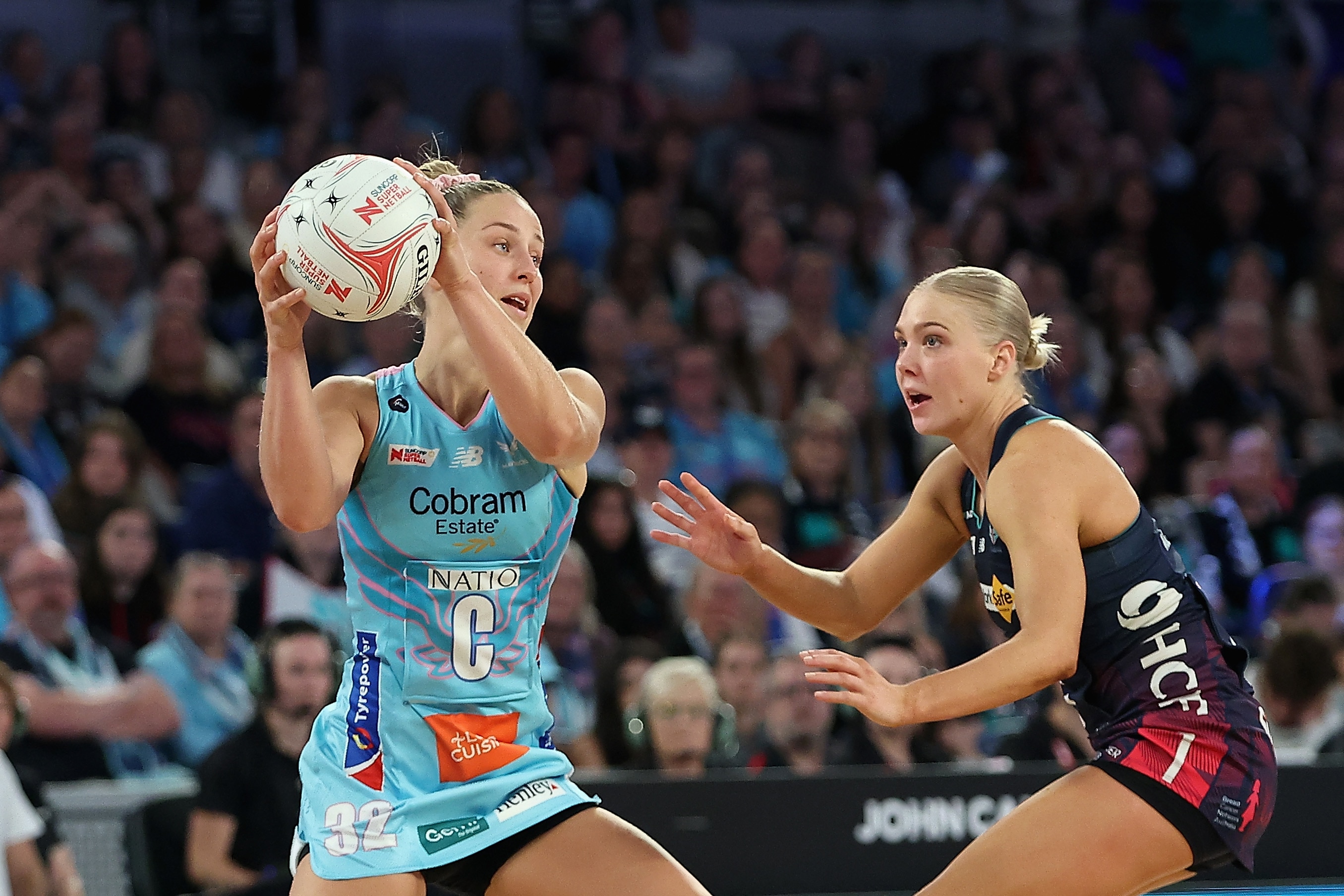 One player holds the ball as another tries to defend her