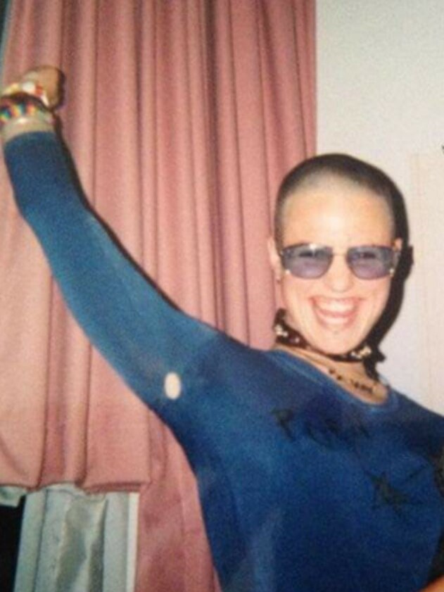 An older photo of a person with a buzzcut and blue sunglasses on.